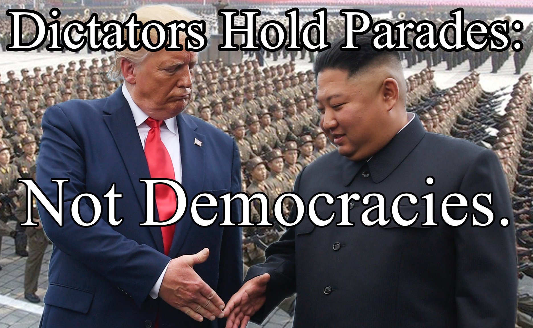 The protest sign shows a composite image of Donald Trump and Kim Jong Un shaking hands with rows of marching soldiers in the background. Bold text at the top reads 'Dictators Hold Parades' and at the bottom, 'Not Democracies.' The image critiques authoritarian displays of power, contrasting them with democratic values. The military parade emphasizes the message against dictatorial practices.