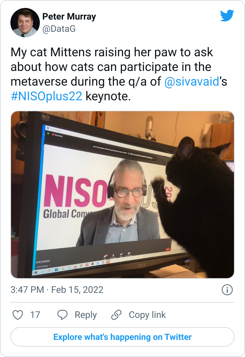 Image of a tweet containing a picture of a black cat pawing the at the screen. On the screen is an image of Todd Carpenter during the NISO-plus conference.